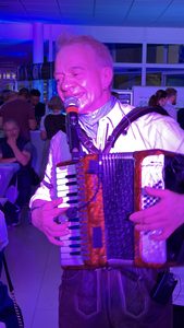 Akkordeonspieler der Oktoberfest Partyband mitten unter den Gästen