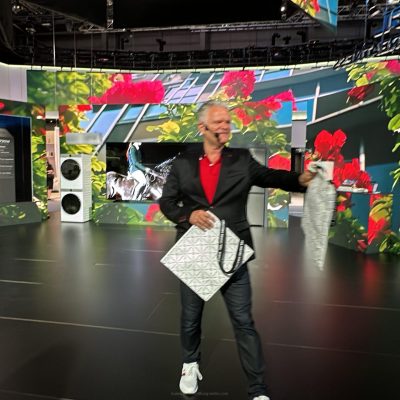 Messemoderator spricht vor Publikum am Messestand auf einer Fachmesse in Berlin